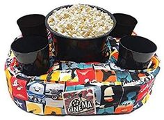 an inflatable bowl with cups and popcorn on it is sitting next to two black mugs