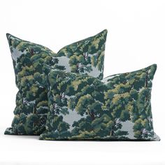 two pillows with trees on them sitting next to each other in front of a white background