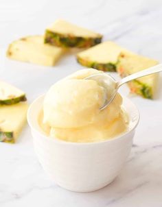 a spoon full of ice cream sitting on top of a white bowl next to pieces of cake