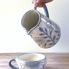 a person pouring water into a cup on top of a wooden table