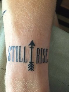 a man with a tattoo on his arm that says still rise and an arrow pointing to the right