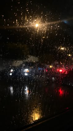 rain is pouring down on the windshield of a car as it sits in traffic at night