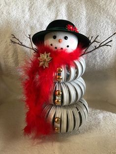 a snowman made out of metal coils with red feathers and a black hat