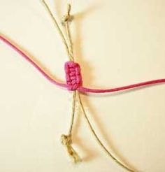 a piece of pink string with two small beads attached to it, sitting on top of a white surface