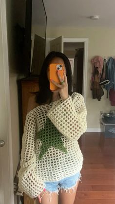 a woman taking a selfie with her cell phone while wearing shorts and a sweater