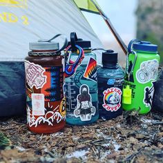 several different types of water bottles sitting on the ground next to a tent and sail