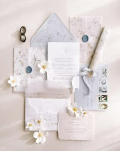 the wedding stationery is laid out on top of the bed with white and yellow flowers