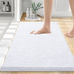 a person standing on top of a white rug in a bathroom next to a toilet