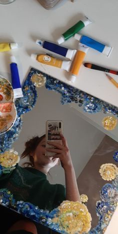 a woman taking a selfie in front of a mirror covered with confetti