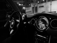 the interior of a car with gauges and steering wheel in black and white photo