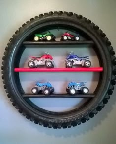 some toy cars are sitting on top of a tire shelf that is hanging from the wall