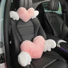 two pink heart shaped pillows in the back seat of a car with white wings on them