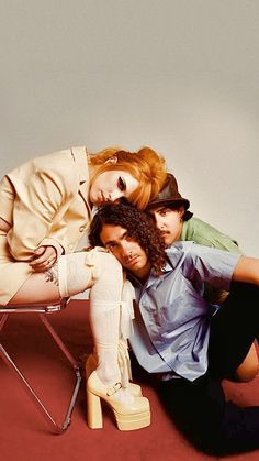 three people sitting on a chair posing for the camera with their legs wrapped around each other