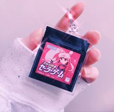 a person holding up a keychain with an anime character on it's back