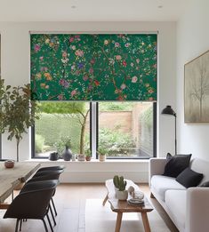 a living room filled with furniture and a large window covered in green floral roman shades