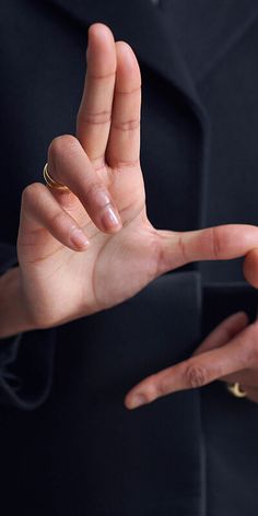 a person in a suit is holding their hand out to the side with both hands