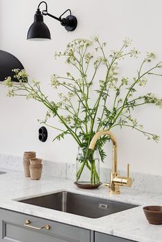 a vase with flowers in it sitting on a kitchen counter next to a sink and faucet