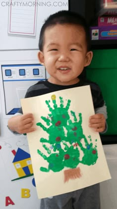 a young boy holding up a paper with a drawing on it