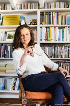 a woman sitting in a chair next to a bookshelf