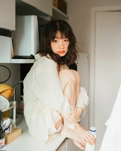 a woman sitting on top of a counter in a kitchen