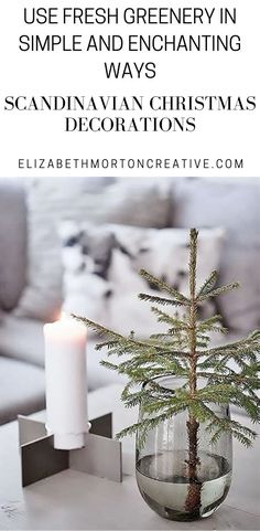 a small christmas tree in a glass vase on a table with a lit candle next to it