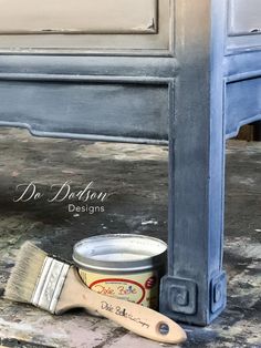 a paint can and brush sitting on the floor next to a painted cabinet door with dr deleon designs