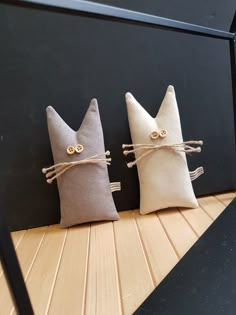 two pillows made to look like cats with eyes tied in twine on top of each other