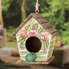 a birdhouse hanging from a chain with flowers painted on the front and side of it