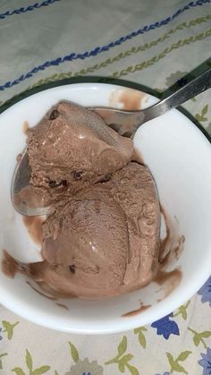 two scoops of chocolate ice cream in a white bowl on a floral tablecloth