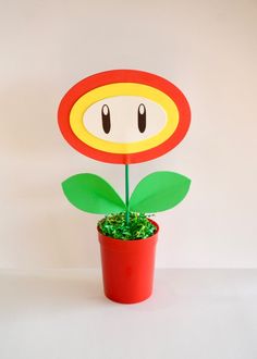 a potted plant with a paper mario mushroom decoration on it's head, sitting in front of a white wall