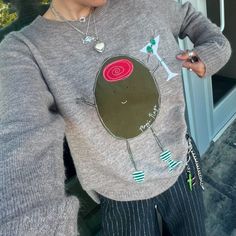 a woman wearing a gray sweater with an image of a snail on the front and side