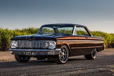 an old car is parked on the side of the road in front of some corn