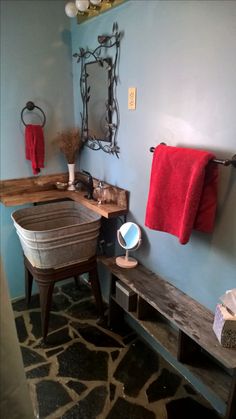 a bathroom with blue walls and stone flooring, including a wooden bench in front of the sink