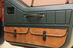 the interior of a vehicle with leather trim and door handles, including an open compartment