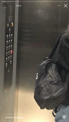 a person with a back pack is standing in front of an elevator door that has buttons on it