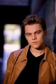 a young man in a brown leather jacket looking at the camera with an intense look on his face