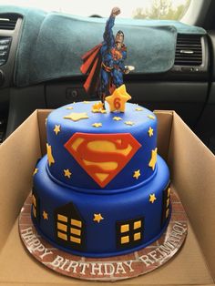 a superman birthday cake in the back seat of a car