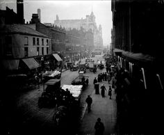 an old black and white photo of people walking down the street