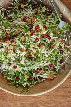 a salad in a wooden bowl on top of a table with a fork and spoon