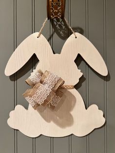 a wooden bunny decoration hanging on a wall next to a light fixture with a lace bow