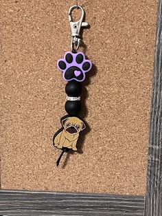 a keychain with a dog's paw on it is hanging from a cork board