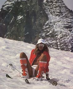 a woman is sitting in the snow on skis