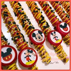 many mickey mouse lollipops are lined up on a white table with red and yellow stripes