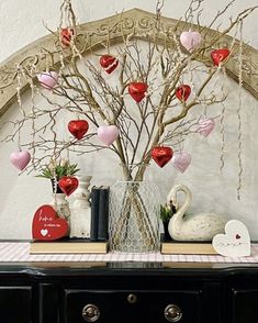 there is a vase with hearts hanging from it on the sideboard next to a book