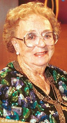 an older woman wearing glasses sitting at a table