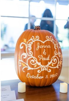 a carved pumpkin with the name and date on it sitting on a table next to candles