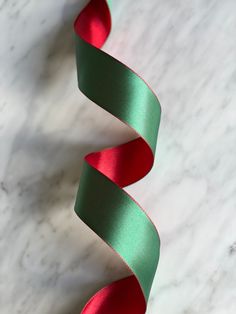 a green and red ribbon on a white marble counter top with the end curled up