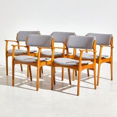 six chairs with grey upholstered seats are lined up in a row on a white floor