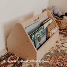 a wooden magazine holder with magazines in it sitting on the floor next to a stuffed animal