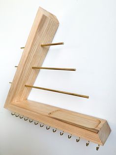 a wooden coat rack with hooks hanging from it's sides on a white wall